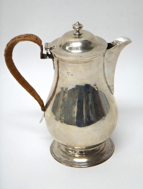 A silver hot water jug, of baluster form, having a rush woven handle and on a circular foot, Chester 1911, gross weight 617 gms.