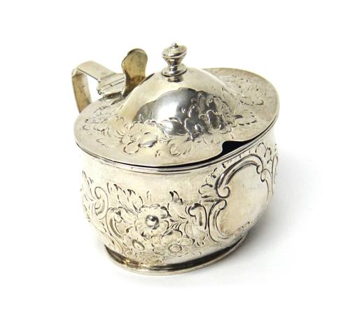 A George III silver mustard pot, of oval form, later embossed with floral, foliate and scrolling decoration, London 1810, with a blue glass liner, wei