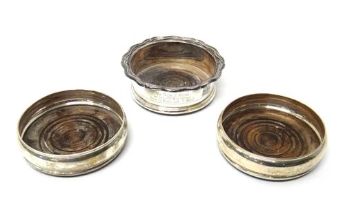 A silver mounted bottle coaster, presentation inscribed and with a turned wooden base, modern and a pair of silver mounted bottle coasters, having tur
