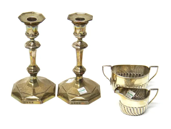 A pair of George VI silver candlesticks, Birmingham 1938, of faceted baluster form, with detachable sconces, and a sugar bowl and matching milk jug wi