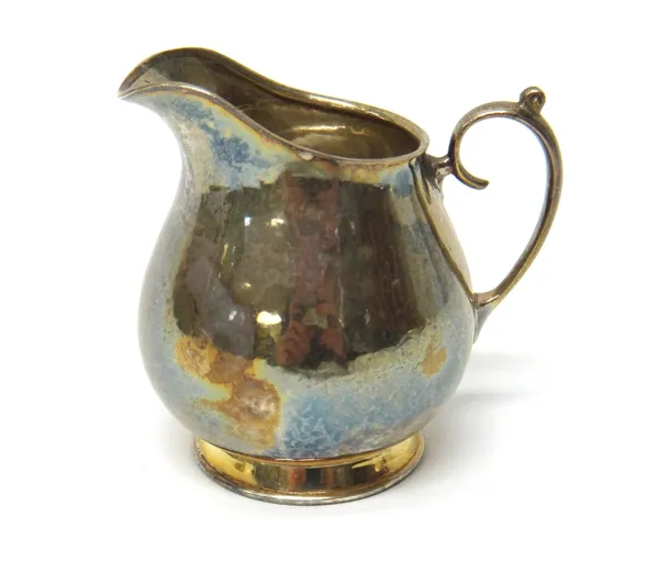 A George VI Liberty & Co silver cream jug, Birmingham 1939, of plain design with scroll handle and planished decoration, gross weight 130gms.