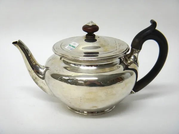 A George III silver teapot, of plain circular form, with a curved spout, a wooden finial and with an associated handle, the body engraved with a coat