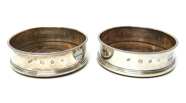 A pair of silver circular bottle coasters, each decorated with a beaded rim and having a turned wooden base, diameter 12.7cm, London 1972.