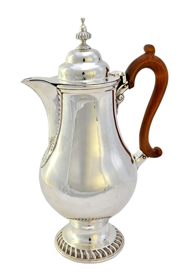 A silver hot water jug, of baluster form, on a gadrooned spreading circular foot and with a wooden handle, the hinged domed cover having a partly flut