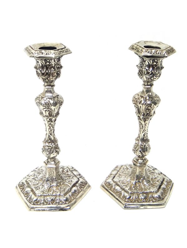 A pair of Victorian silver table candlesticks, each profusely decorated with floral and foliate scrolls and on a hexagonal base, height 24cm, loaded,