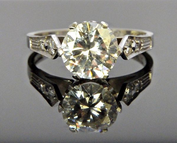 A platinum and diamond ring, claw set with the principal circular cut diamond at the centre, between diamond set two stone shoulders, detailed within