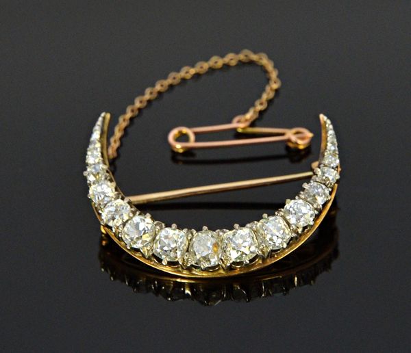 A gold backed and silver fronted diamond set brooch, designed as a crescent, mounted with a row of cushion shaped diamonds graduating in size to the c