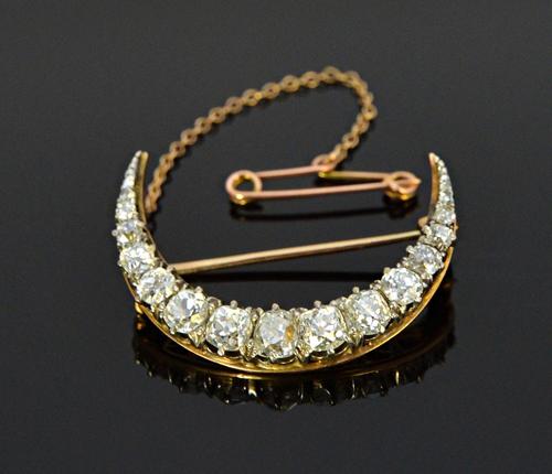 A gold backed and silver fronted diamond set brooch, designed as a crescent, mounted with a row of cushion shaped diamonds graduating in size to the c