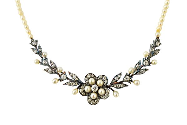 A late Victorian silver fronted and gold backed diamond and cultured pearl necklace, the front designed as a flowerhead between tapered foliate sides,