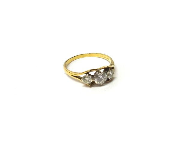 A gold and diamond set three stone ring, claw set with the principal circular cut diamond at the centre, between two smaller circular cut diamonds, in