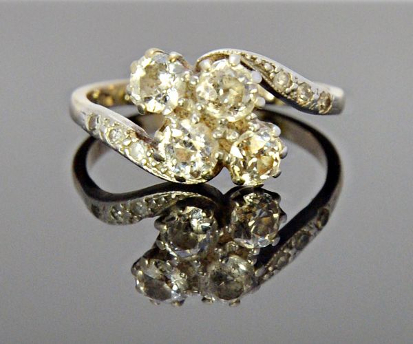 A white gold and diamond ring, claw set with the four principal cushion shaped diamonds at the centre, between diamond set three stone shoulders, in a