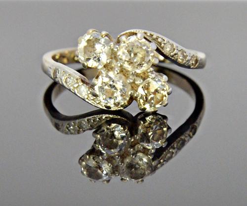 A white gold and diamond ring, claw set with the four principal cushion shaped diamonds at the centre, between diamond set three stone shoulders, in a