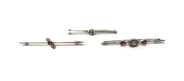 A white gold and diamond set four stone bar brooch, mounted with cushion shaped diamonds, detailed 15 CT, a white gold, ruby and diamond set three sto