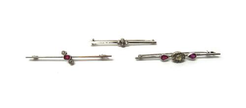 A white gold and diamond set four stone bar brooch, mounted with cushion shaped diamonds, detailed 15 CT, a white gold, ruby and diamond set three sto