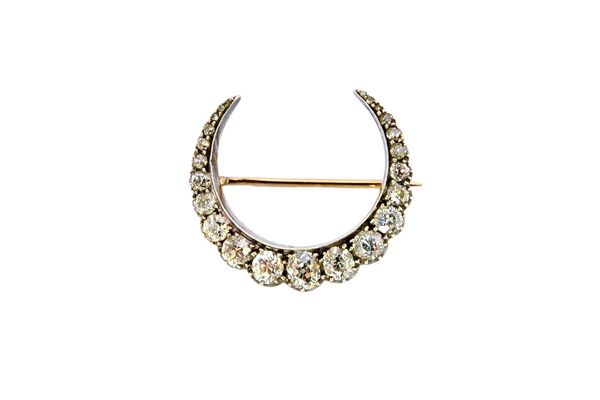 A Victorian silver fronted and gold backed diamond brooch, designed as a crescent, mounted with a row of cushion shaped diamonds, graduating in size t