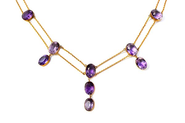 A gold and amethyst necklace, collet set with oval cut amethysts, on a two row oval link chain, having a snap clasp, fitted with a safety chain.  Illu