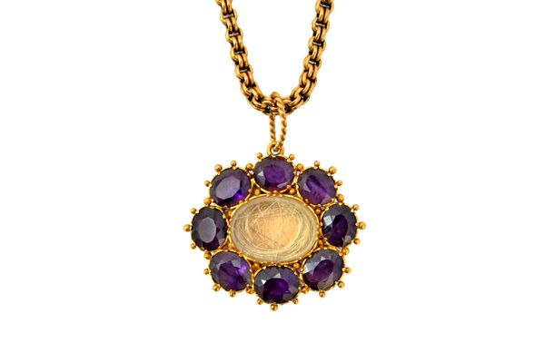 An early 19th century amethyst set oval pendant, glazed with a hair locket compartment to the centre, in a border of eight oval cut amethysts, having