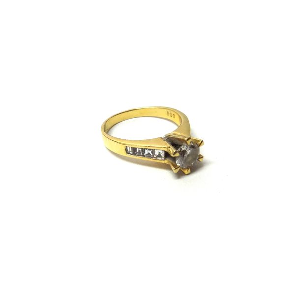 A gold and diamond set ring, claw set with the principal circular cut diamond at the centre, between emerald cut diamond set four stone shoulders, det