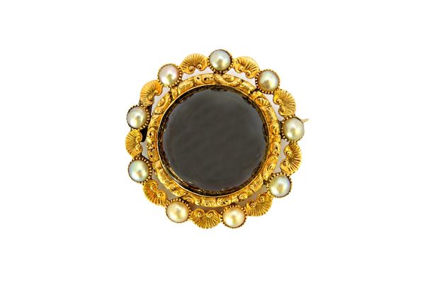 A Victorian cabochon garnet and half pearl set brooch in a circular scrolling and foliate setting, gross weight 15.4 gms, with a case.  Illustrated