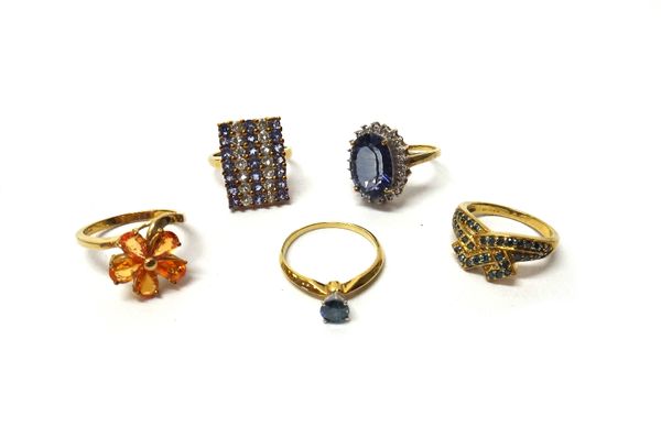 A 9ct gold ring, claw set with a circular cut artificially treated blue diamond, a 9ct gold and orange gem set ring, designed as a flowerhead shaped c