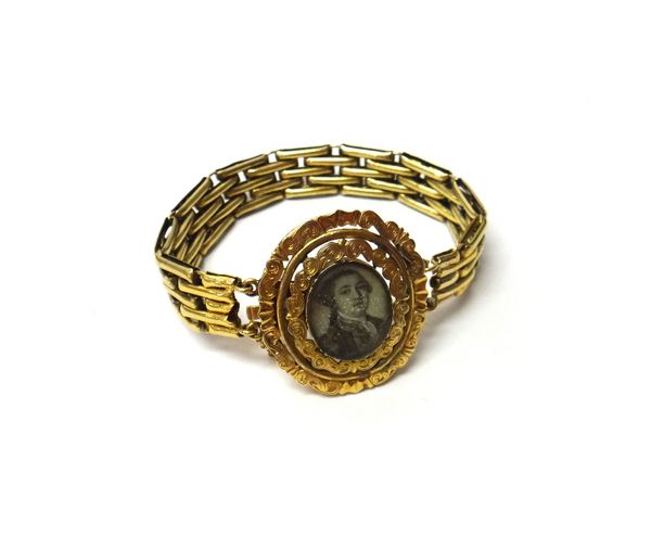 A portrait miniature bracelet, the oval front panel glazed with the portrait miniature of a gentleman, the scroll pierced border with engraved decorat