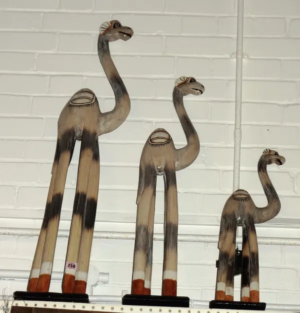 A group of three carved wooden models of camels.