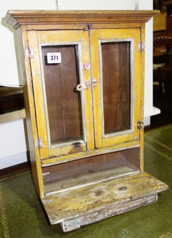 A yellow painted small glazed two door wall cupboard, 35cm.