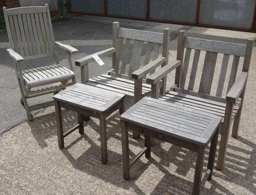 A pair of teak armchairs, a folding chair and two small tables.