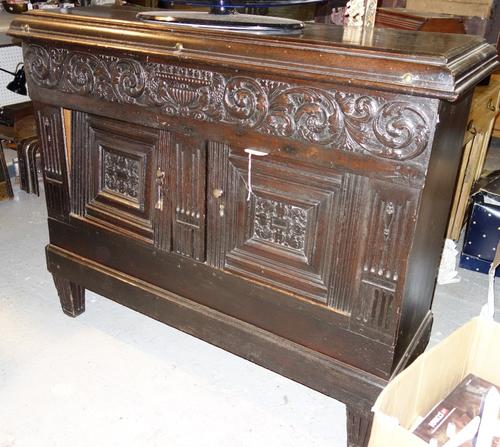 A 17th century and later North European oak side cupboard, with carved frieze over a pair of panelled doors, on tapering square supports, 135cm wide.