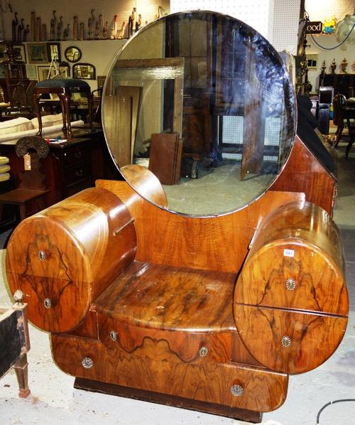 A mid-20th century figured walnut dressing table, with bevelled circular mirrored back over six various shaped drawers, 132cm wide.