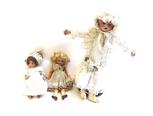 Three bisque head dolls, early 20th century, comprising; a French S.F.B.J no.60 with silk bonnet and embroidered dress, 34cm high, an Armand Marseille