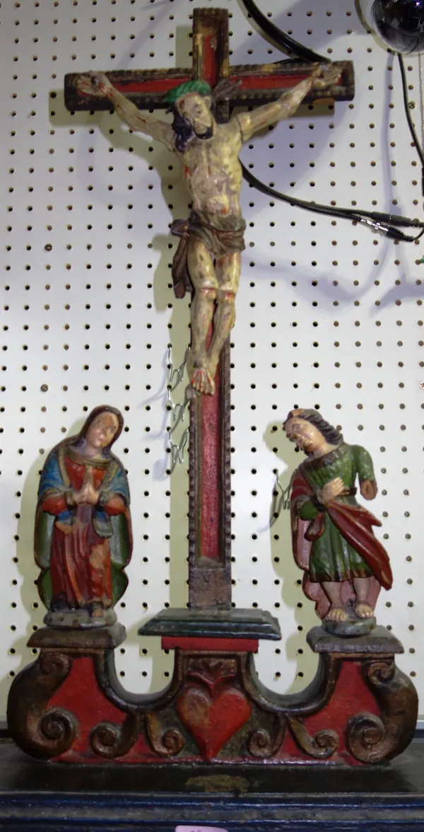 An 18th century and later polychrome decorated altar piece, depicting Christ mounted on a crucifix, flanked by disciples on an ebonised base.