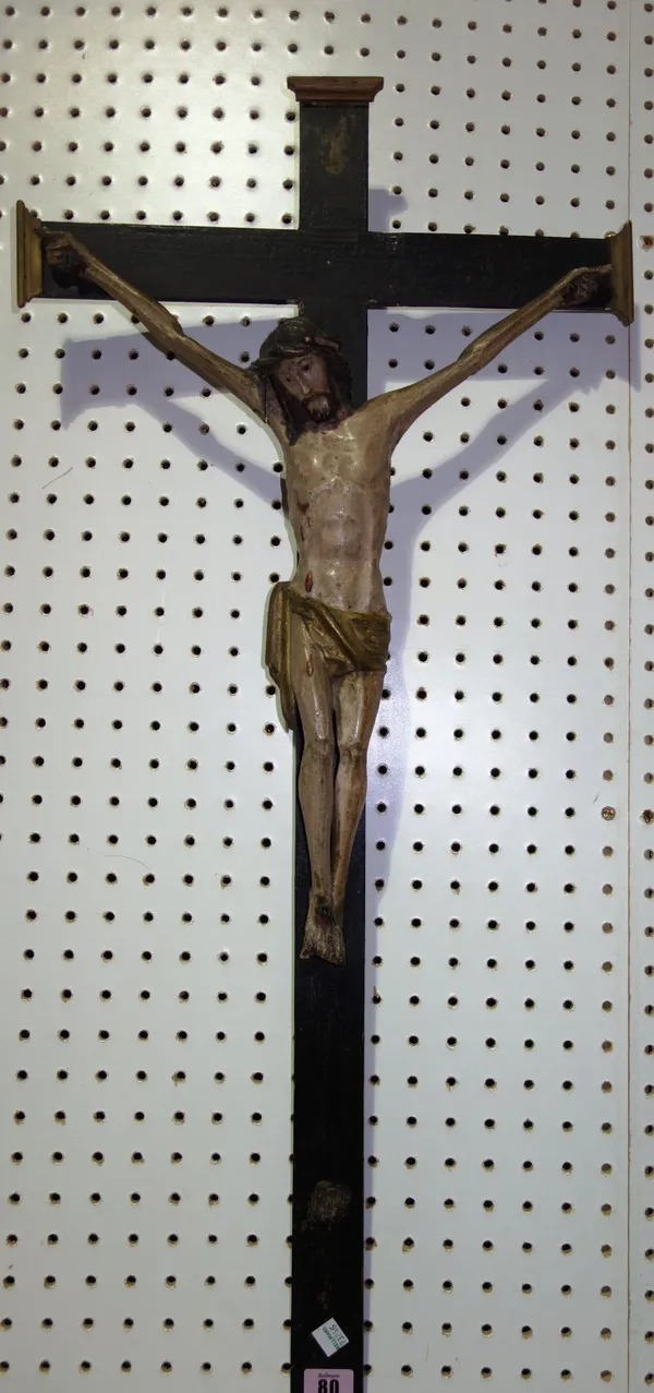 An 18th century and later polychrome figure of Christ, mounted on an ebonised crucifix.
