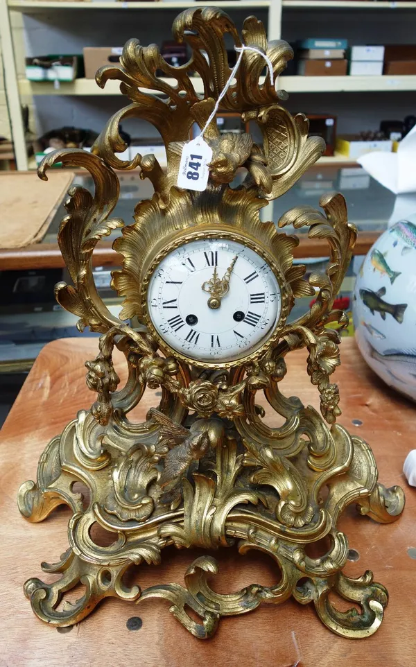 A French gilt bronze mantel clock, late 19th century, of Rococo scroll form, pierced and decorated with applied flora and fauna, with a white enamel d