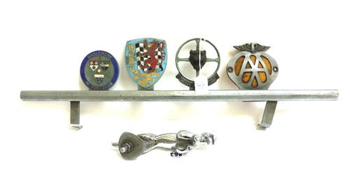 A silvered bronze Jaguar car mascot, 19cm long, and four car badges on a grille bar; Haslemere Motor Club, B.A.R.C, Jaguar driver's club and an A.A ba