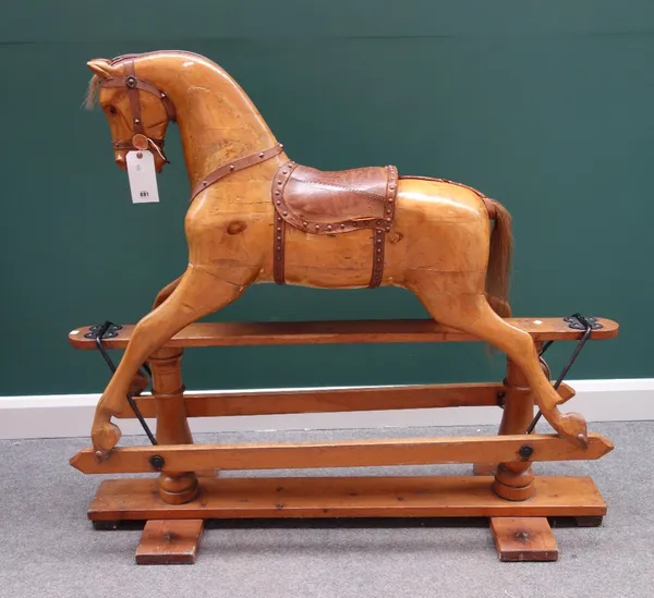 A pine rocking horse, early 20th century, paint traces but with a stripped and polished finish, with horse hair mane and leather saddle, on a wooden a