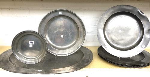 A large oval pewter dish, 19th century, 66cm wide, a set of six circular pewter plates with broad rims and indistinct touch marks, 38cm diameter, anot