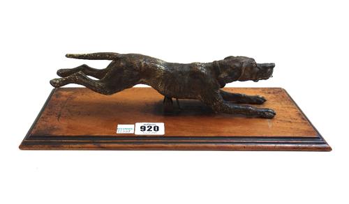 An Austrian cold painted bronze desk paper clip, late 19th century, in the form of a running hound, on a walnut stepped base, 32cm wide overall.