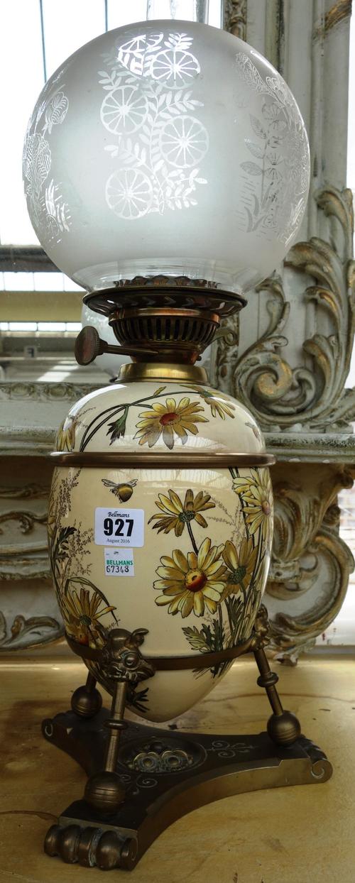 A pottery and brass mounted oil lamp, 19th century, the inverted egg shaped body decorated with fauna and flora, against a cream ground, mounted in a