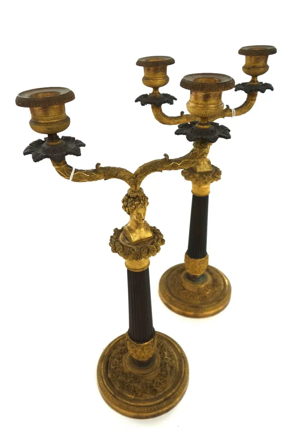 A pair of Restauration ormolu and patinated bronze two light candelabra, circa 1825, each with domed circular foot cast with floral garlands, issuing