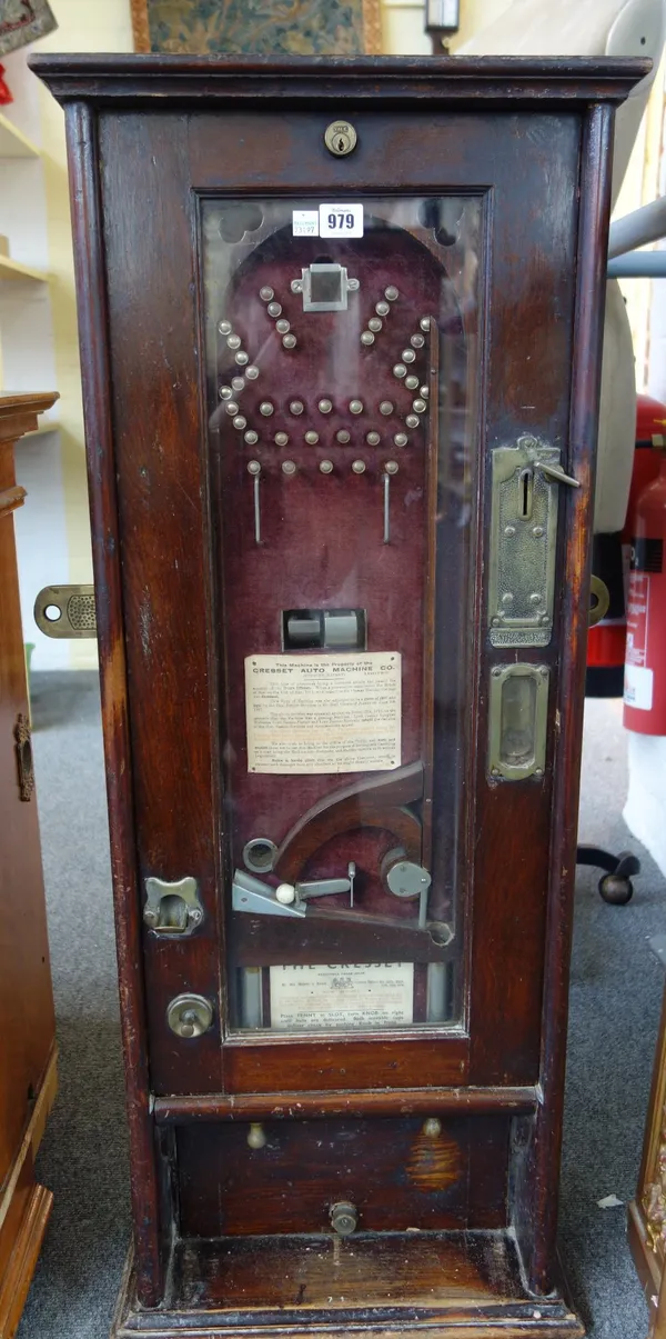 A Cresset penny slot bagatelle wall machine, with an arrangement of metal pins against a red velvet ground, stained oak case with applied instruction