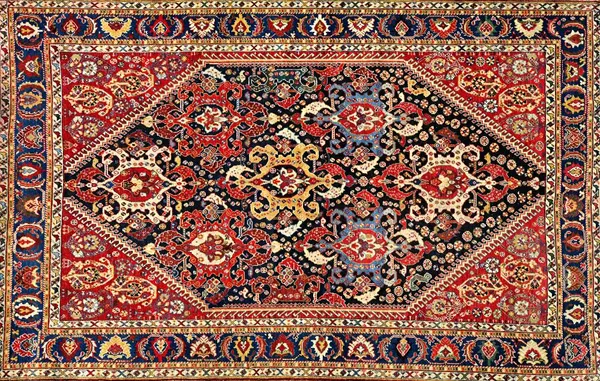 A Ghasghai rug, South Persian, the indigo field with seven shaped hooked medallions, minor motifs, hooked madder spandrels, with two boteh, an indigo