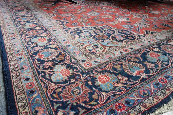 A Mashad carpet, Persian, the madder field with a bold lobed medallion, matching spandrels, all with bold floral sprays, an indigo palmette and floral