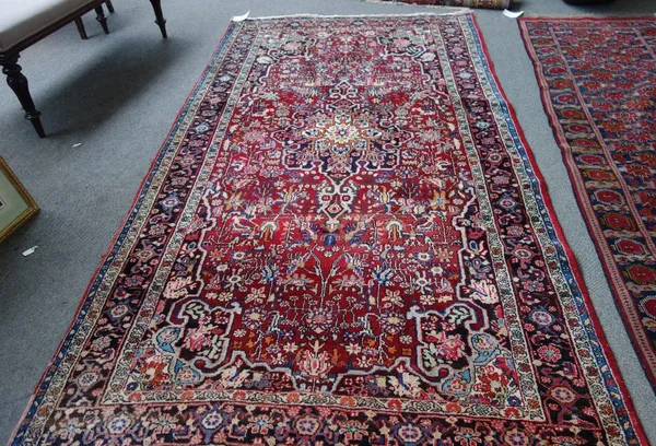 A Bidjar rug, Persian, the madder field with a black medallion, matching spandrels, all with floral sprays, a black complementary border, 283cm x 149c