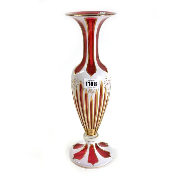 A cranberry and white enamel glass vase, late 19th/early 20th century, with gilt foliate decoration against a baluster body, with knopped stem and cir