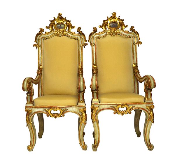 A pair of mid 19th century Italian grey painted parcel gilt throne chairs, the cartouche crest with painted figures over high back, open arms and serp