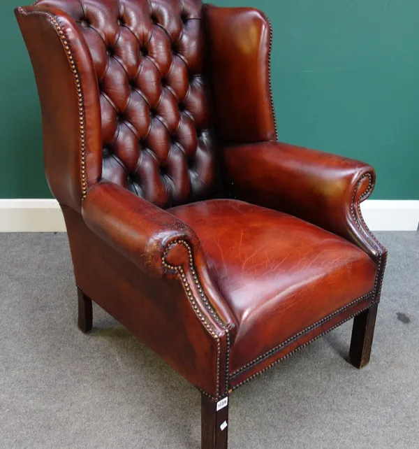 An early 18th century style studded brown leather upholstered wing back armchair, on block supports.