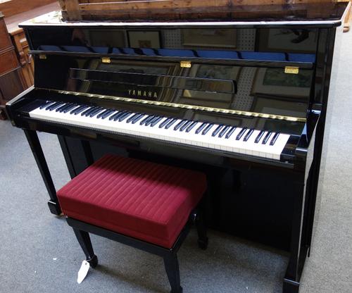 A 20th century Yamaha overstrung iron framed upright piano, with lacquered ebonised case, the frame marked 'V114N-S E295814', 145cm wide, with a match