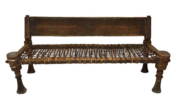 A late 19th/early 20th century African hardwood bench, the back panel with chipwork decoration over an open lattice leatherwork seat, on turned suppor