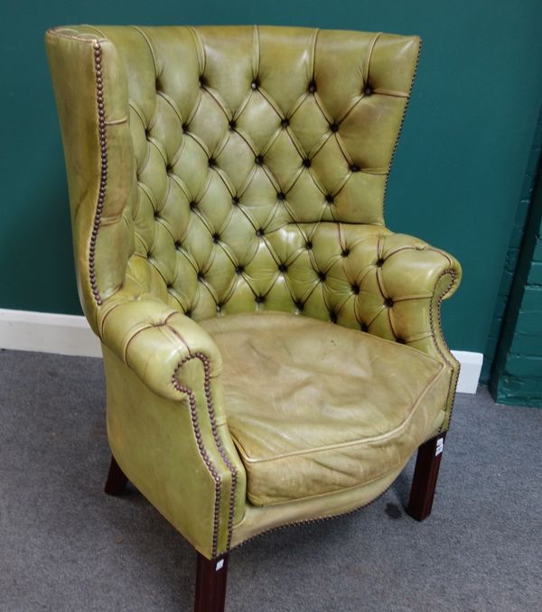 A George III style brass studded green leather upholstered high tub back armchair, with serpentine seat, on channelled square supports.